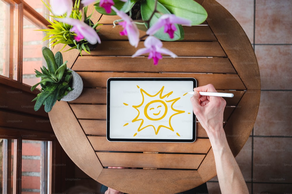 une personne dessinant un soleil sur une tablette