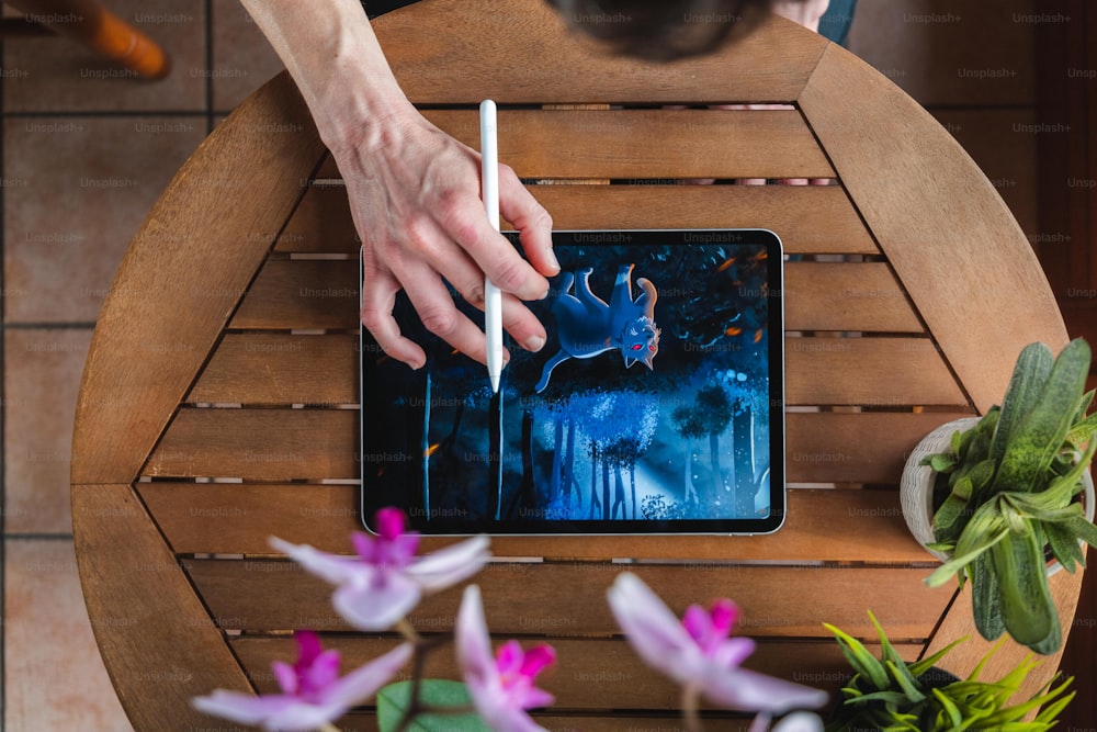 une personne utilisant une tablette sur une table en bois