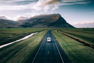 a van driving down a road in front of a mountain