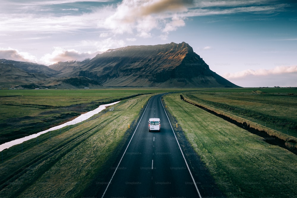 a van driving down a road in front of a mountain