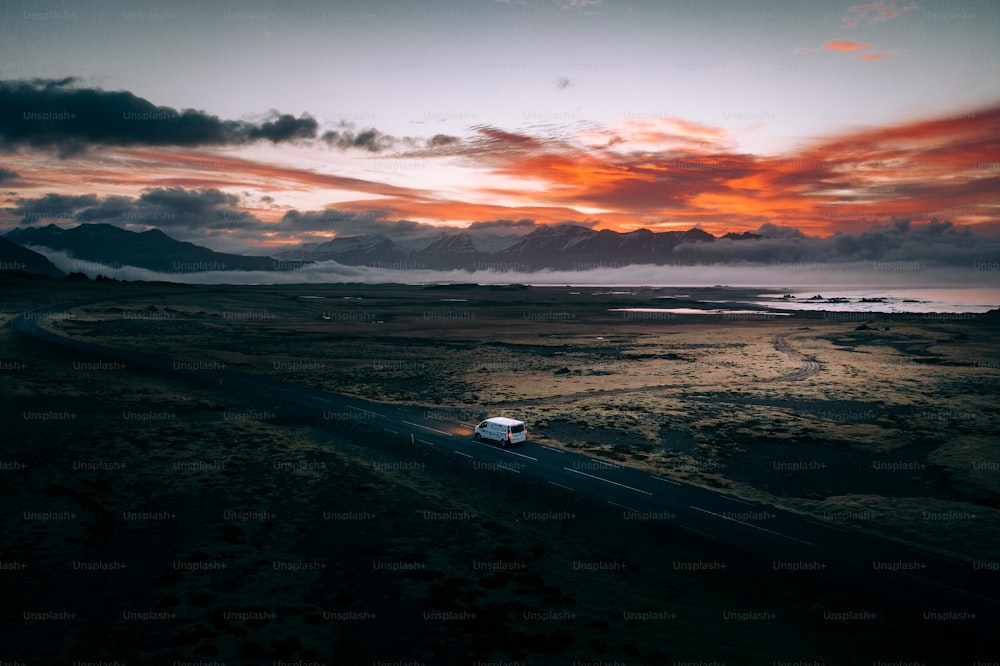 a car driving down a road with a sunset in the background