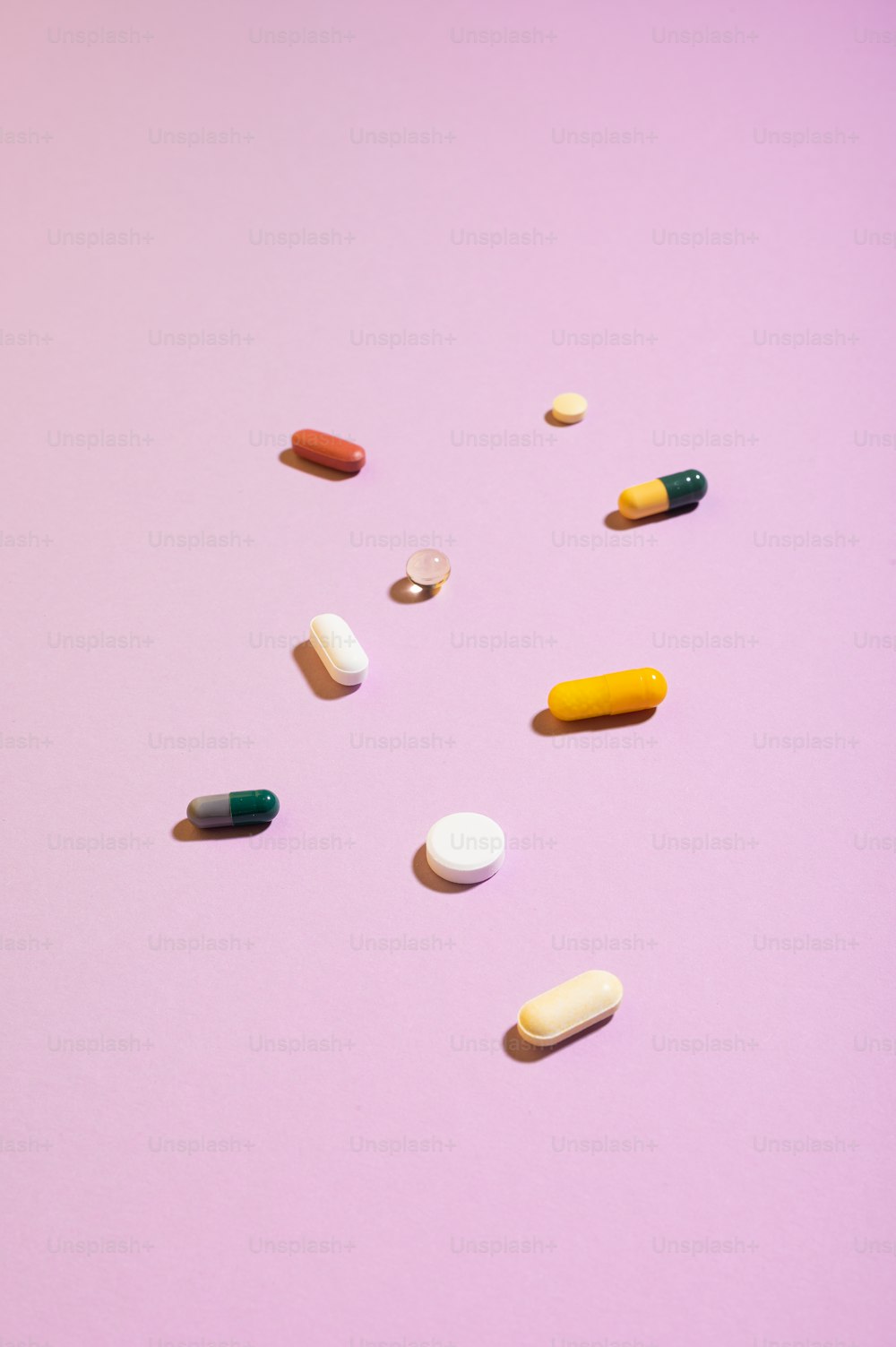 Un gruppo di pillole sedute sopra una superficie rosa