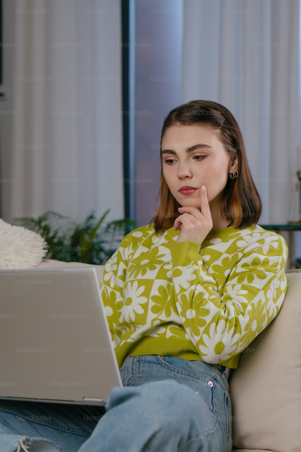 a woman sitting on a couch looking at a laptop