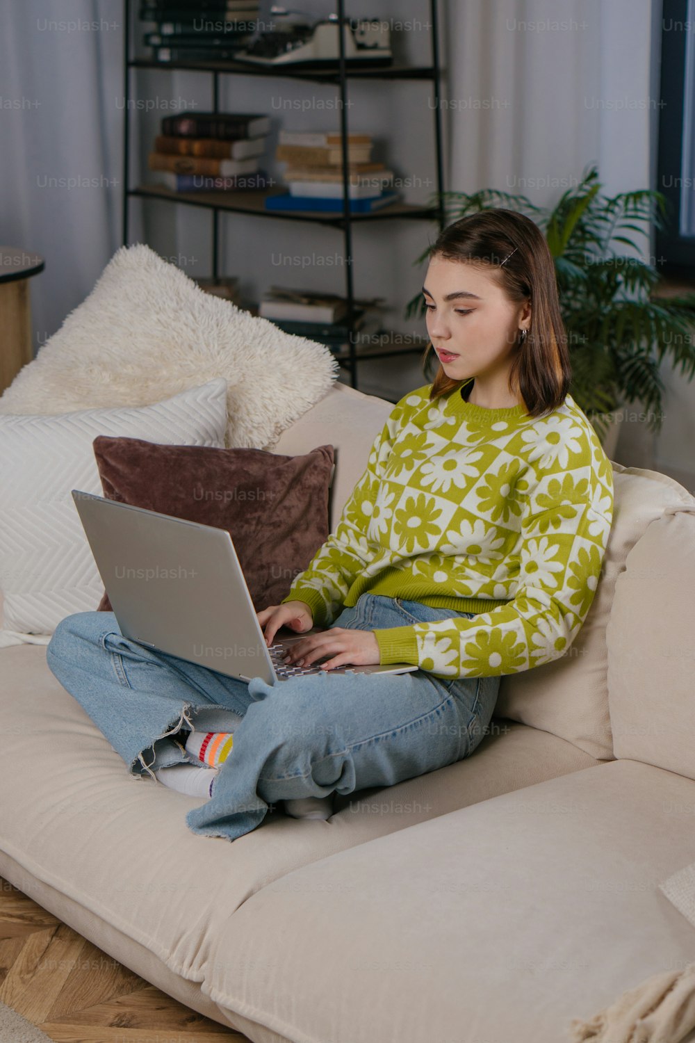 une femme assise sur un canapé à l’aide d’un ordinateur portable