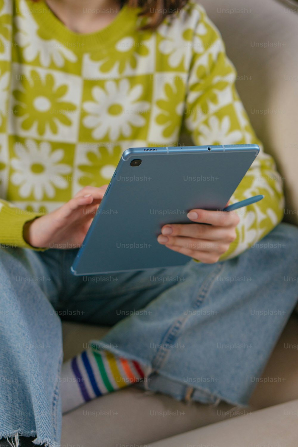a person sitting on a couch holding a tablet