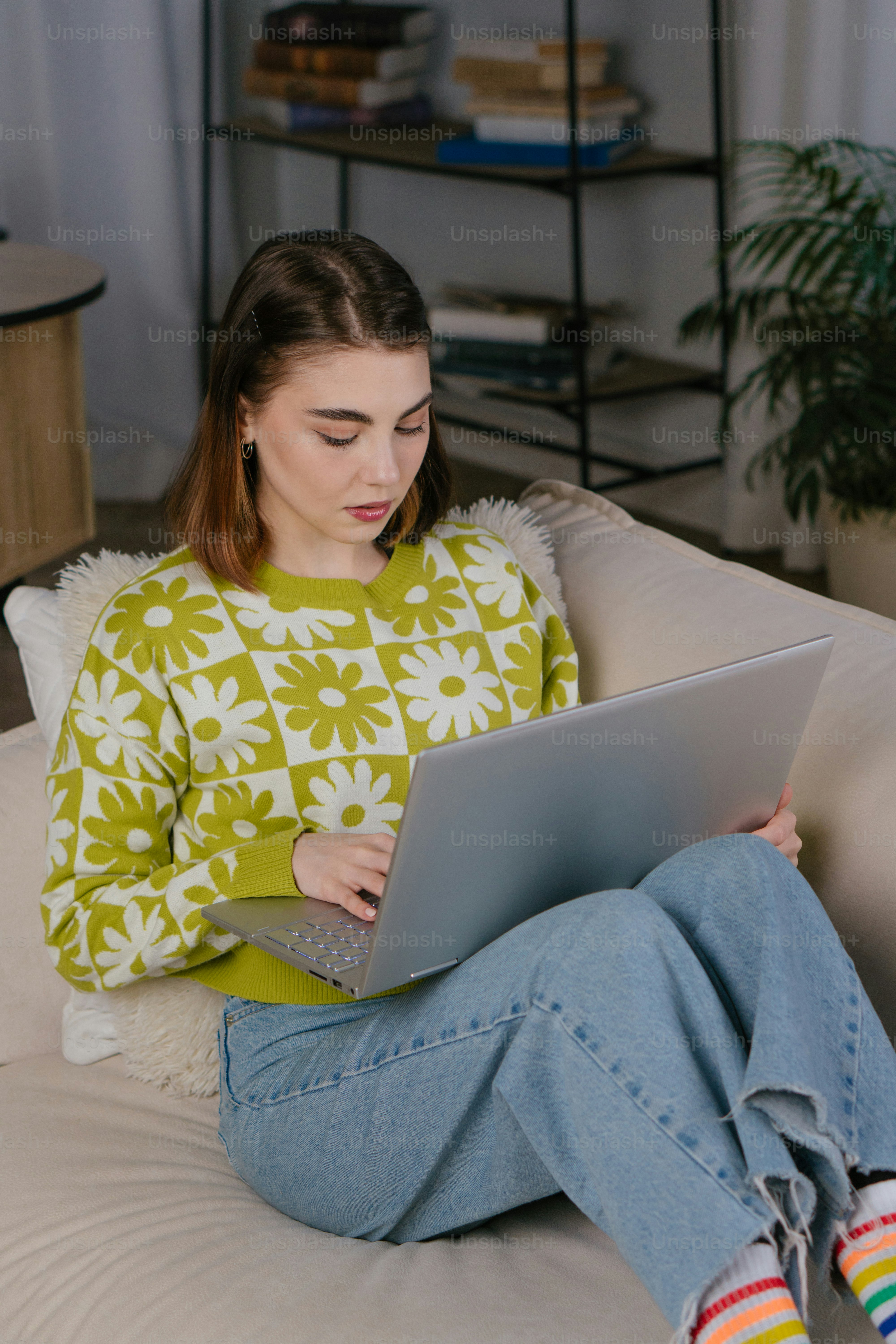 a woman sitting on a couch using a laptop computer