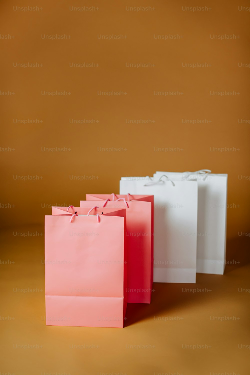 Tre piccole borse della spesa bianche e rosa su sfondo marrone