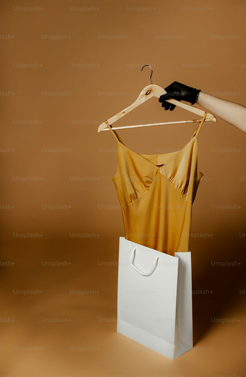la main d’une femme tenant un sac en papier avec une robe dessus;