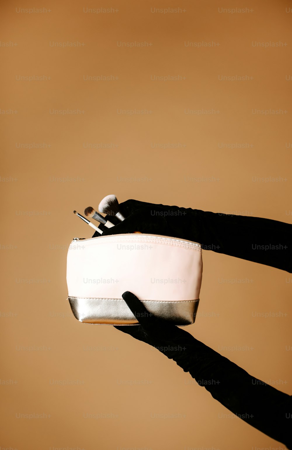 a pair of black gloves holding a white purse