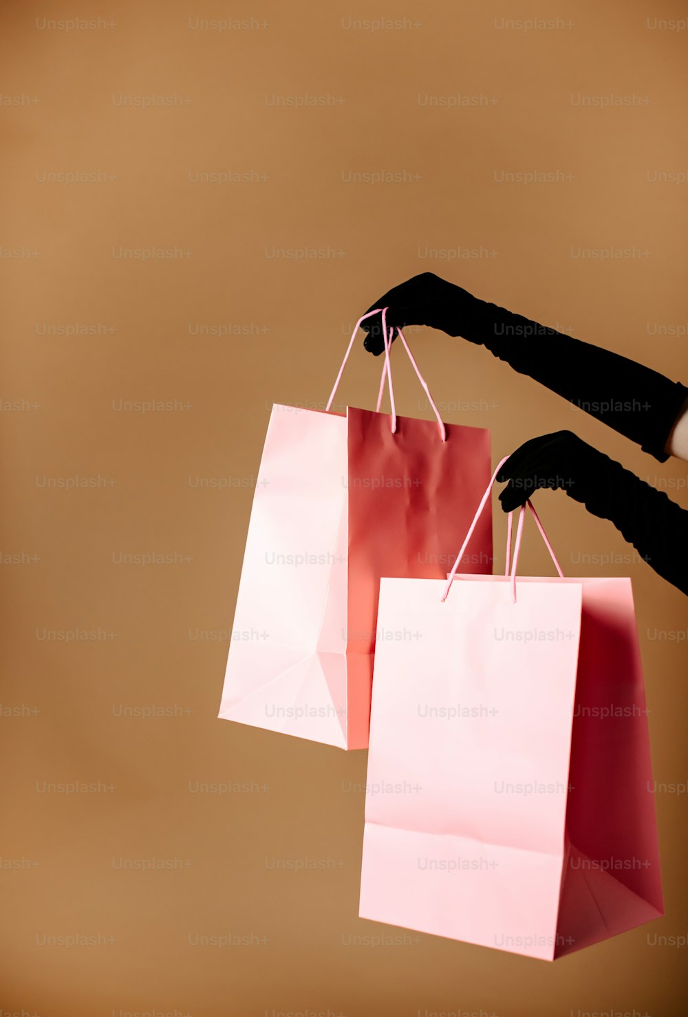 Una persona sosteniendo tres bolsas de compras en la mano