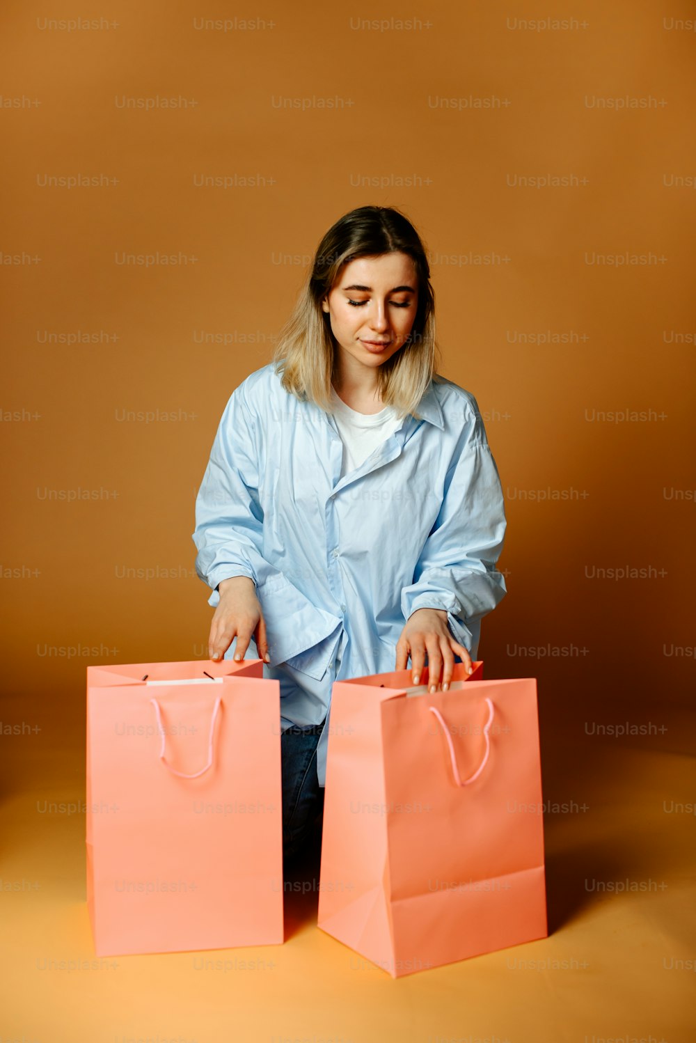 Une femme en chemise bleue tient deux sacs roses