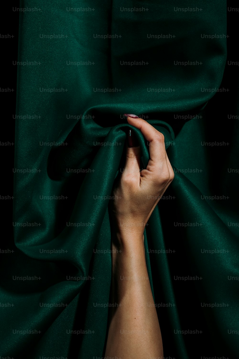 une main de femme couvrant un tissu vert foncé
