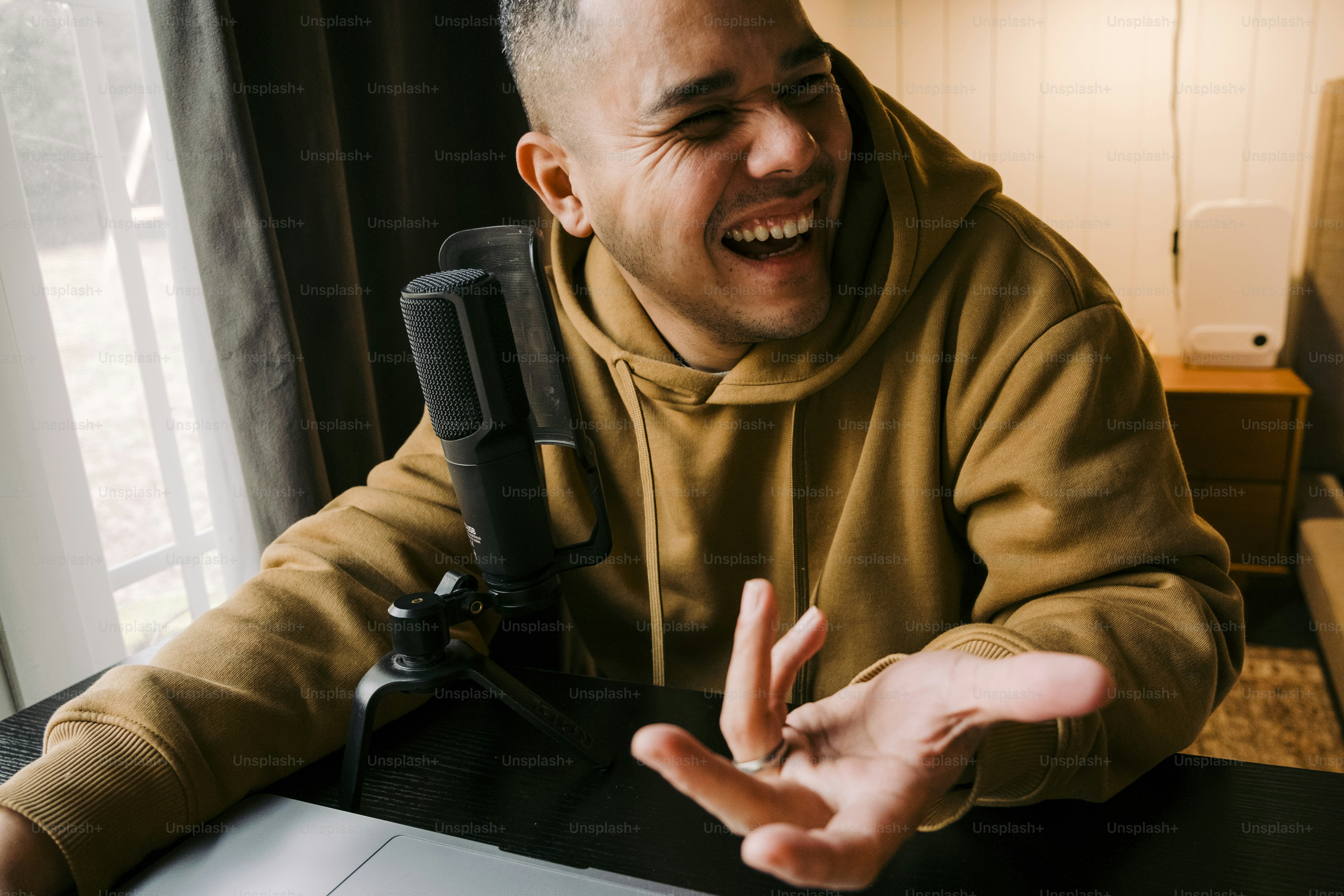 Un hombre sentado en una mesa con una computadora portátil y un micrófono