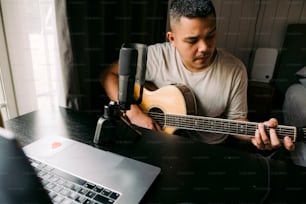 a man sitting at a desk playing a guitar