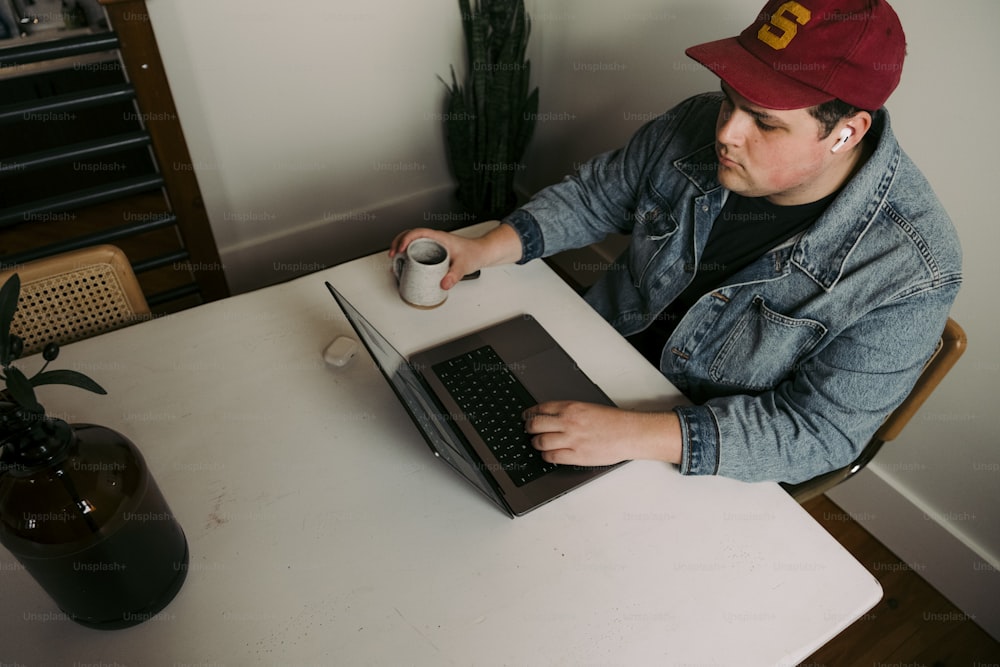 �ノートパソコンを使ってテーブルに座っている男性