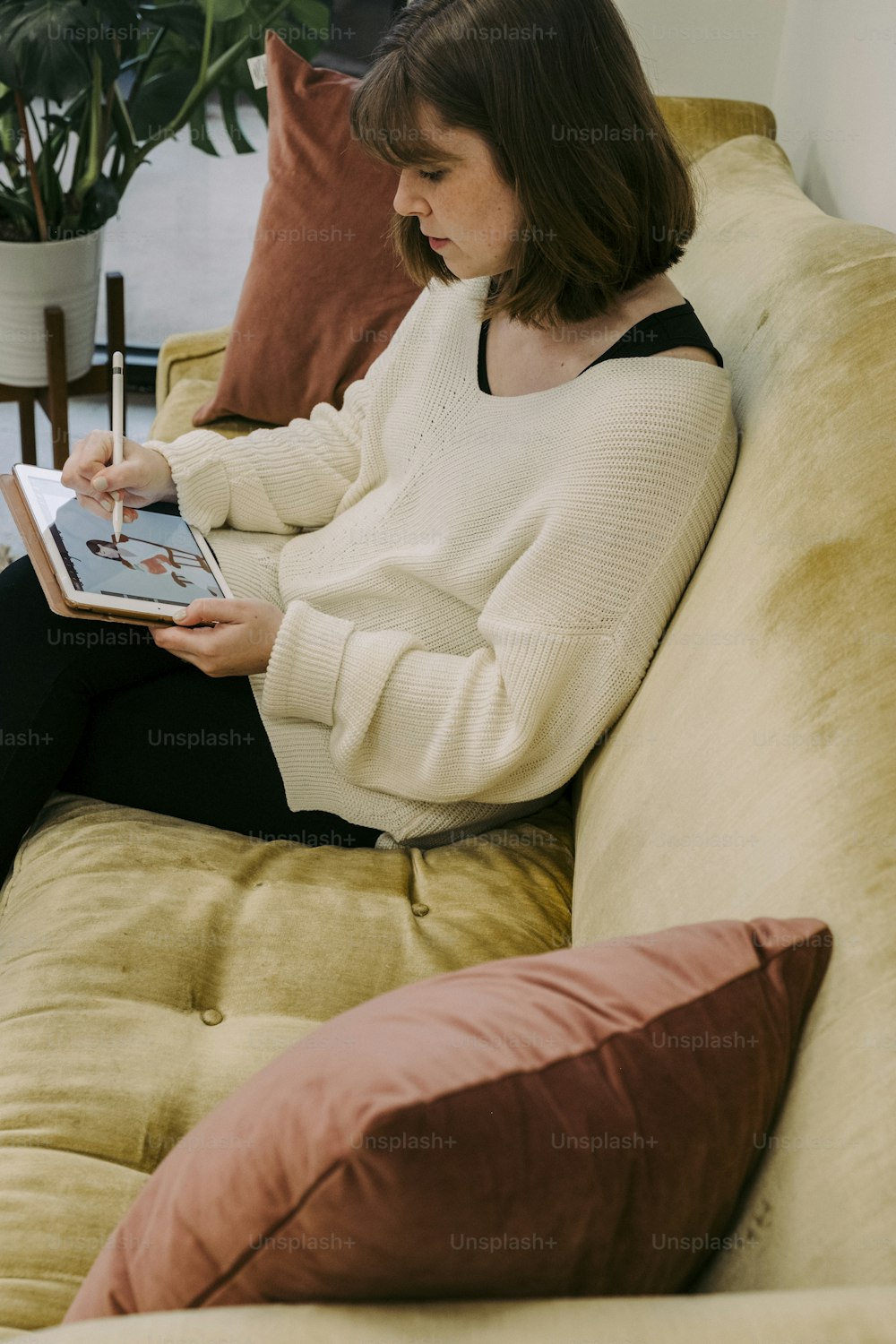 a woman sitting on a couch using a tablet