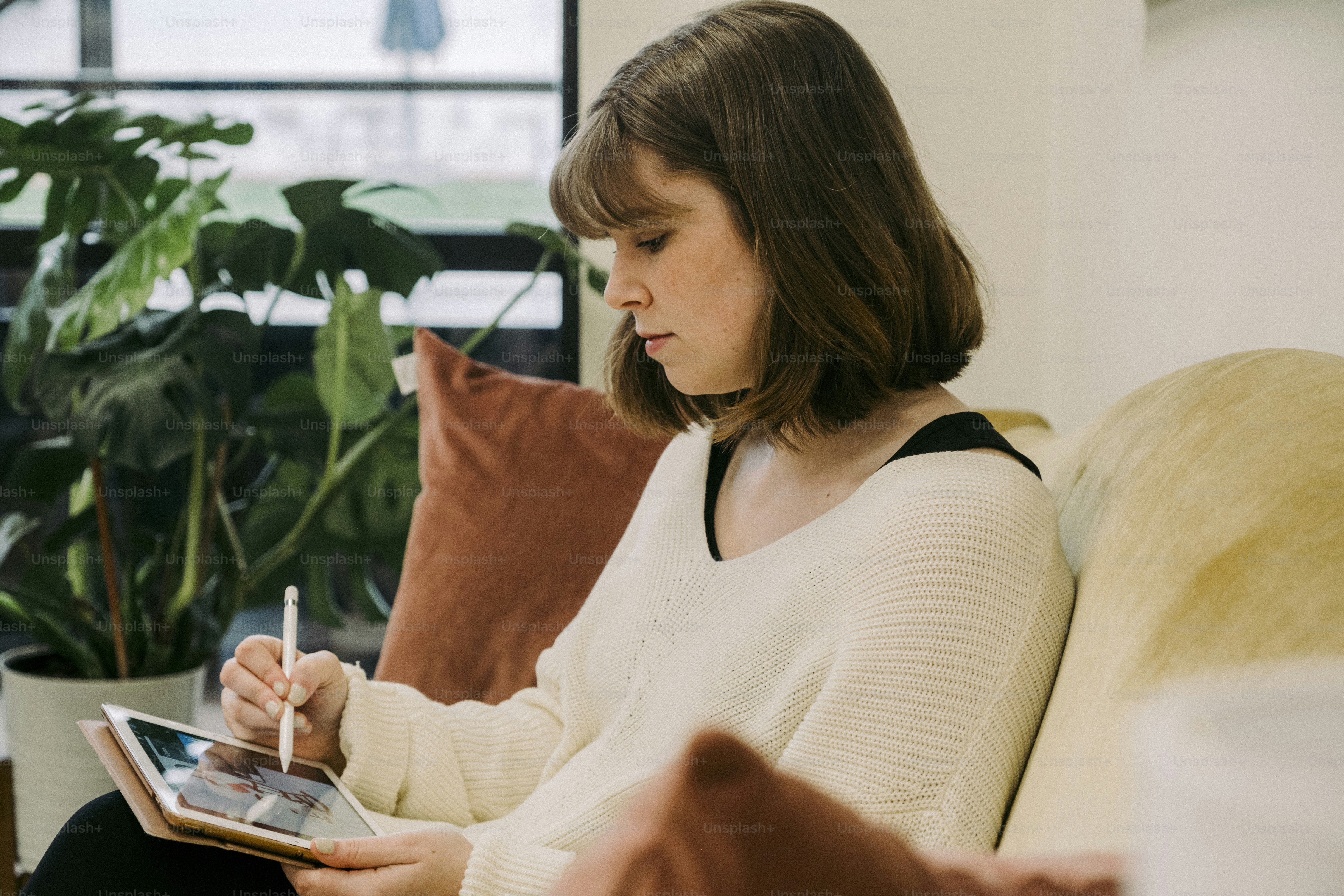 a woman sitting on a couch holding a tablet