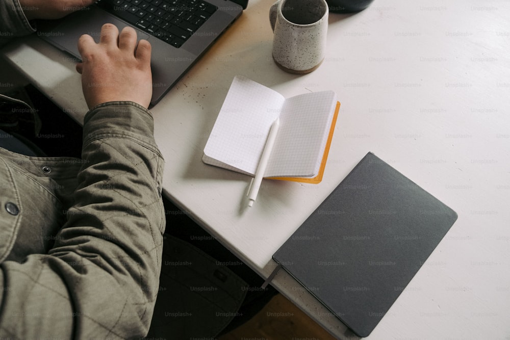 une personne assise à un bureau avec un ordinateur portable et un ordinateur portable