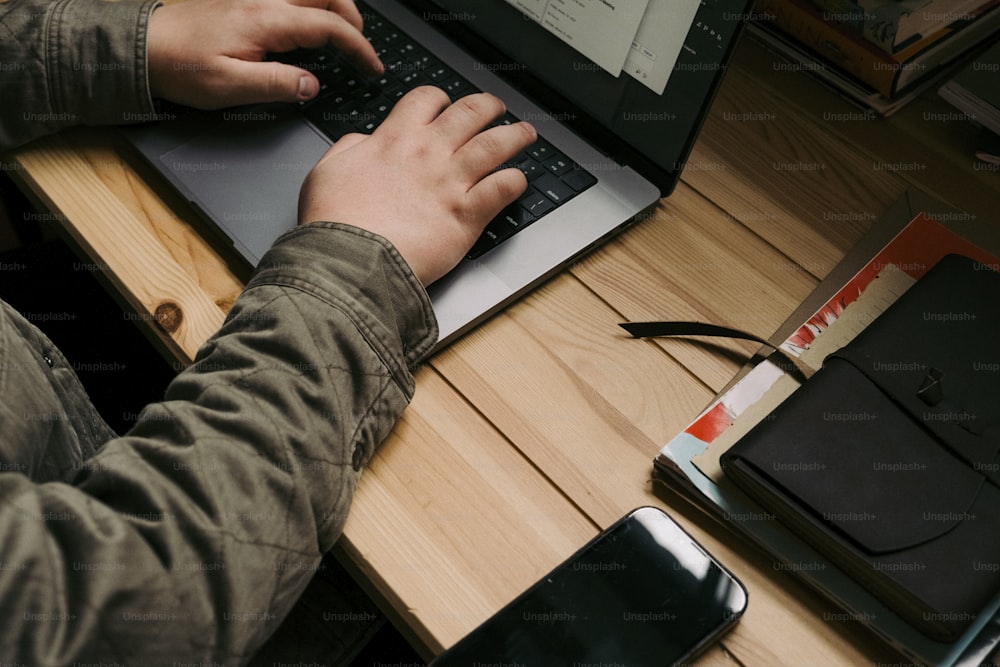Una persona escribiendo en una computadora portátil en un escritorio de madera