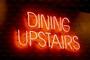 a neon sign that says dining upstairs