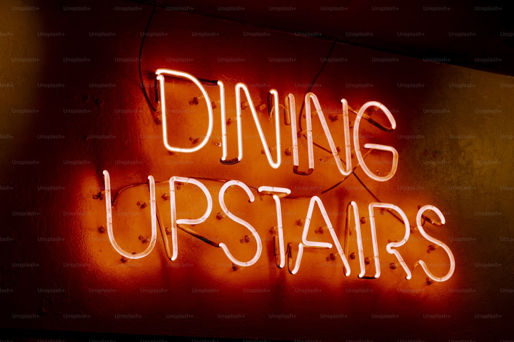 uma placa de néon que diz jantar no andar de cima