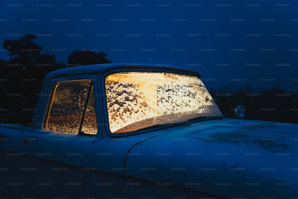 a blue truck with a window covered in snow