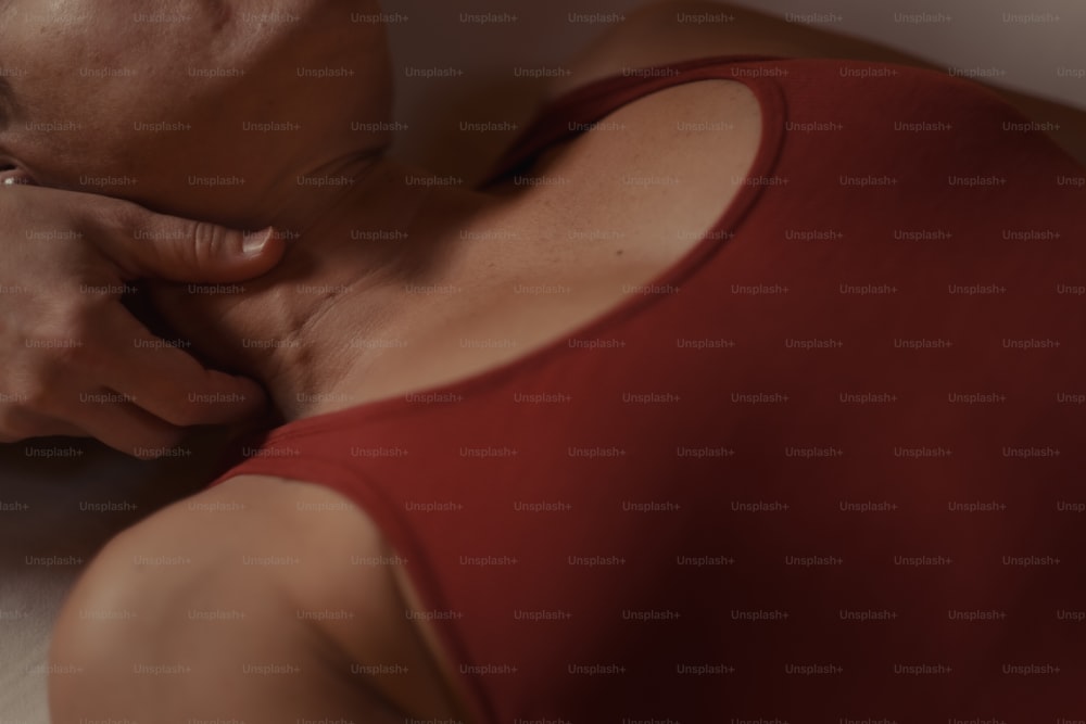 a woman in a red tank top rubbing her neck