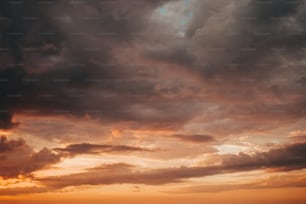 a plane flying through a cloudy sky at sunset