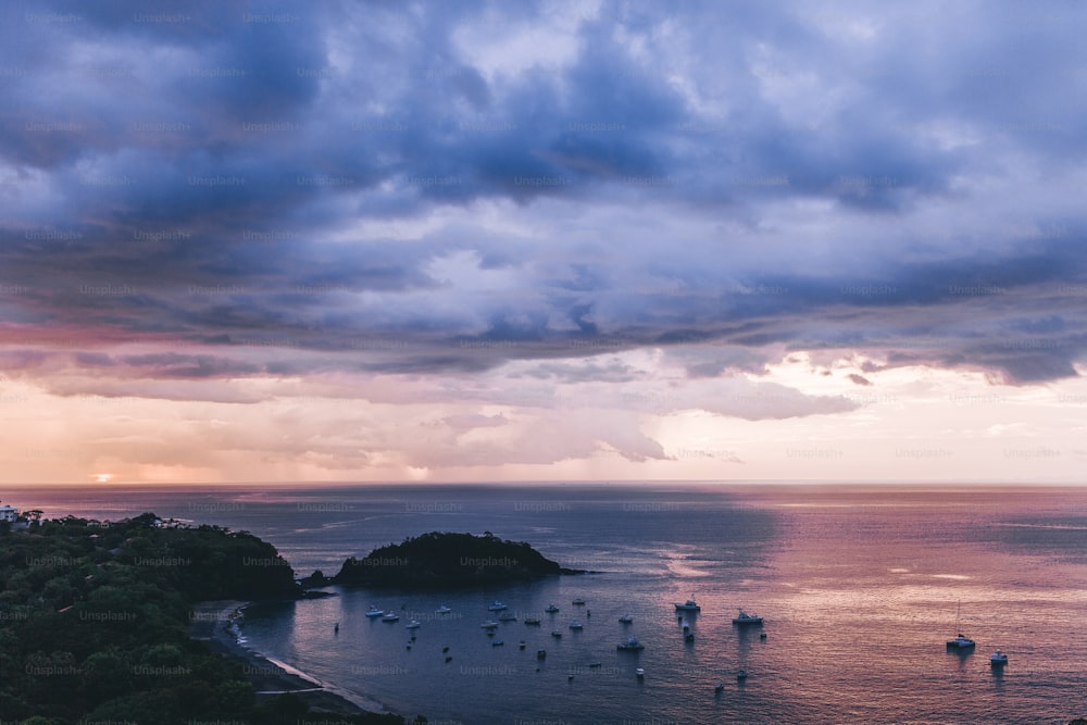 a group of boats floating on top of a body of water under a cloudy sky