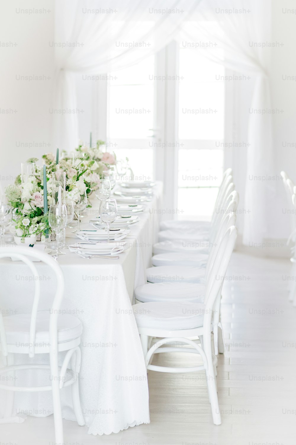 una mesa larga con sillas blancas y flores