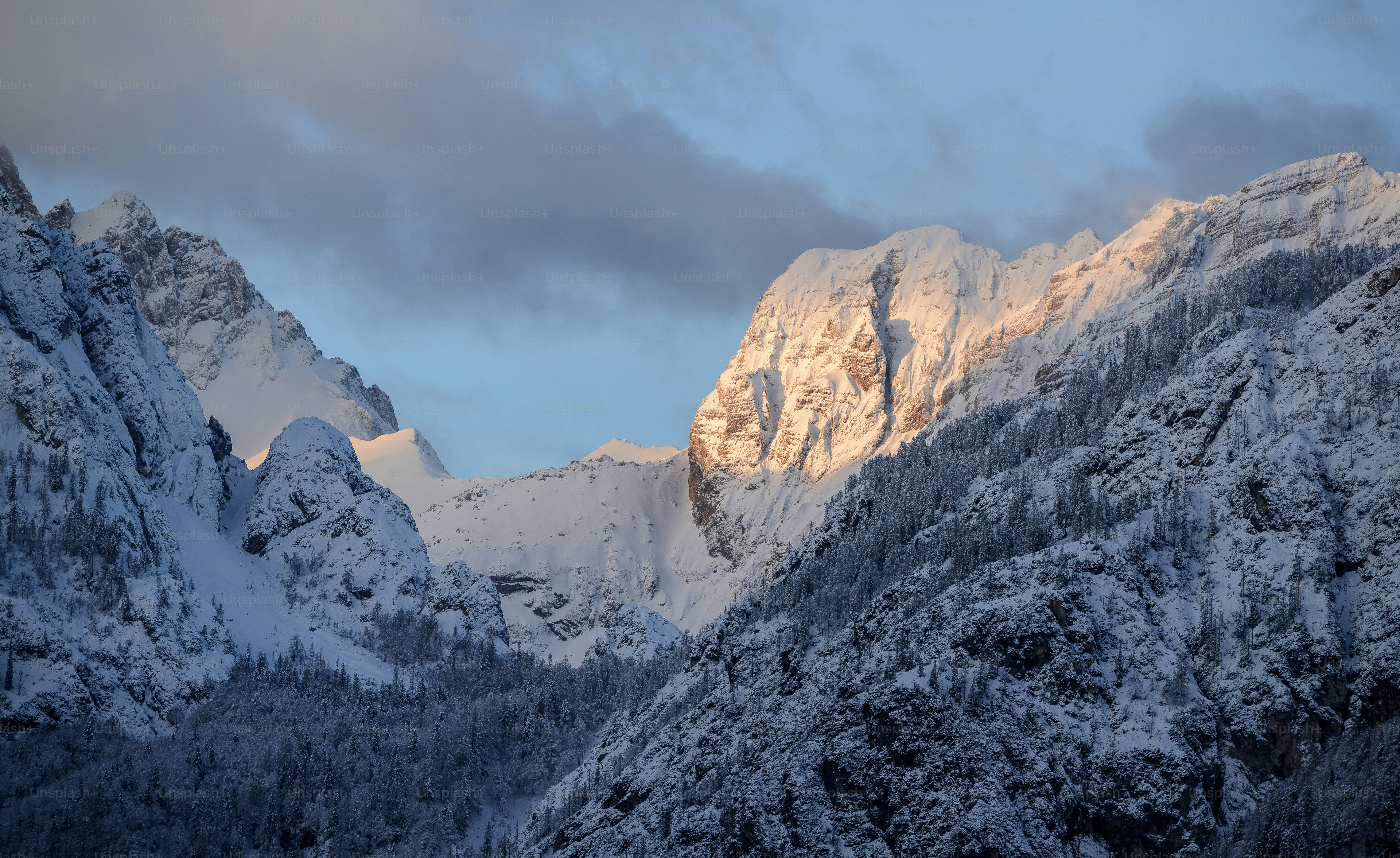 a mountain covered in snow under a cloudy sky