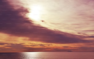 a plane flying over a body of water under a cloudy sky