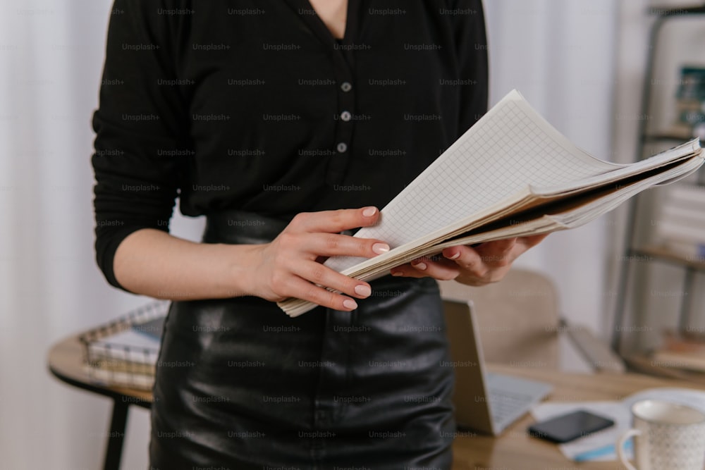Una donna in camicia nera tiene in mano un libro