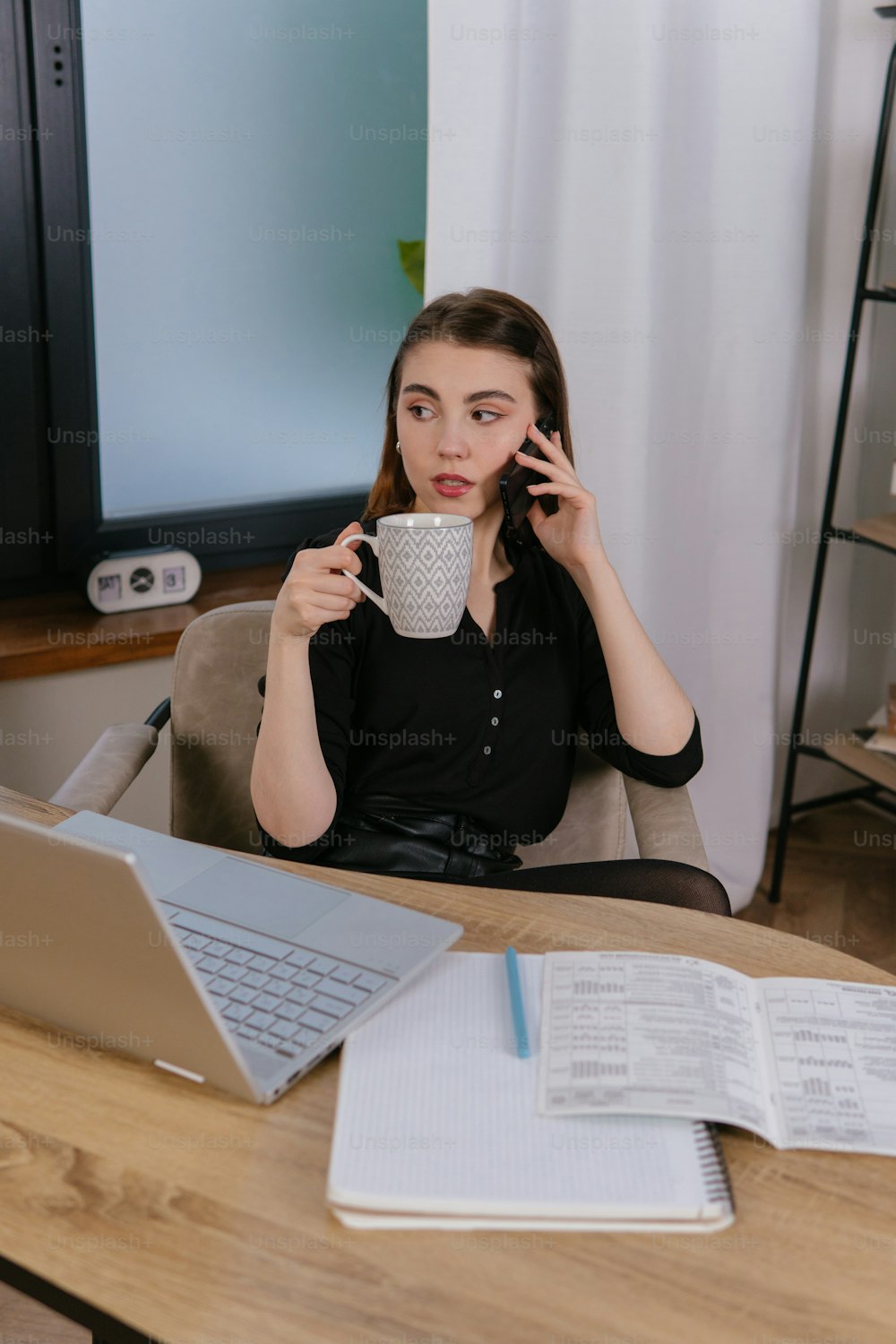 uma mulher sentada em uma mesa com um laptop e uma xícara de café