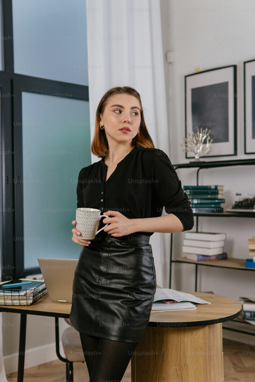 a woman sitting at a desk with a cup of coffee