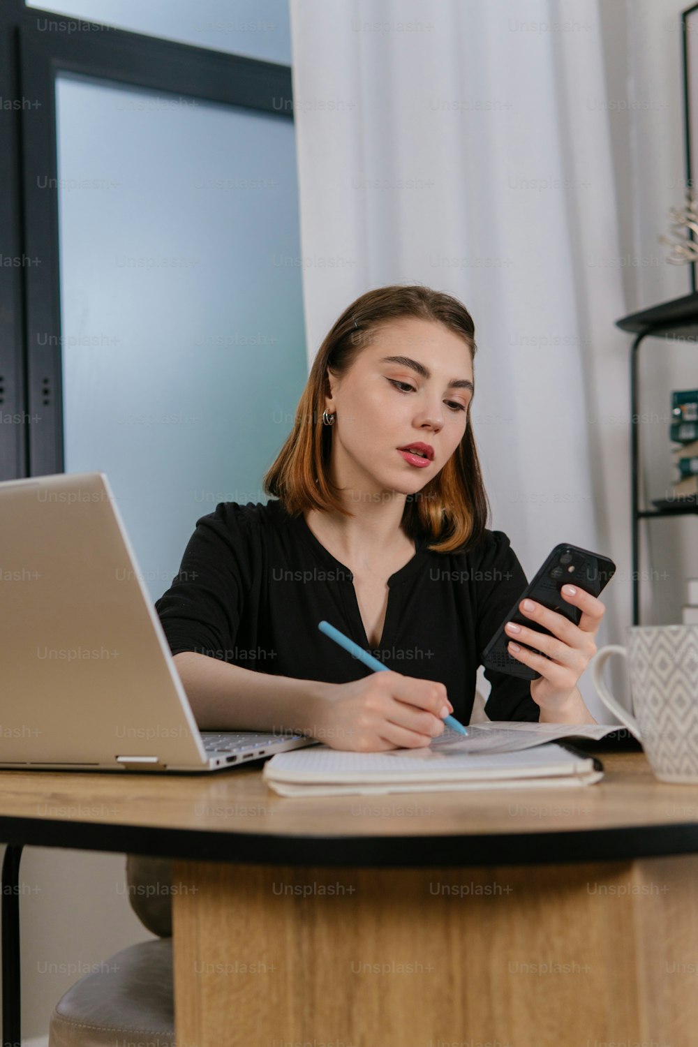 uma mulher sentada em uma mesa usando um telefone celular