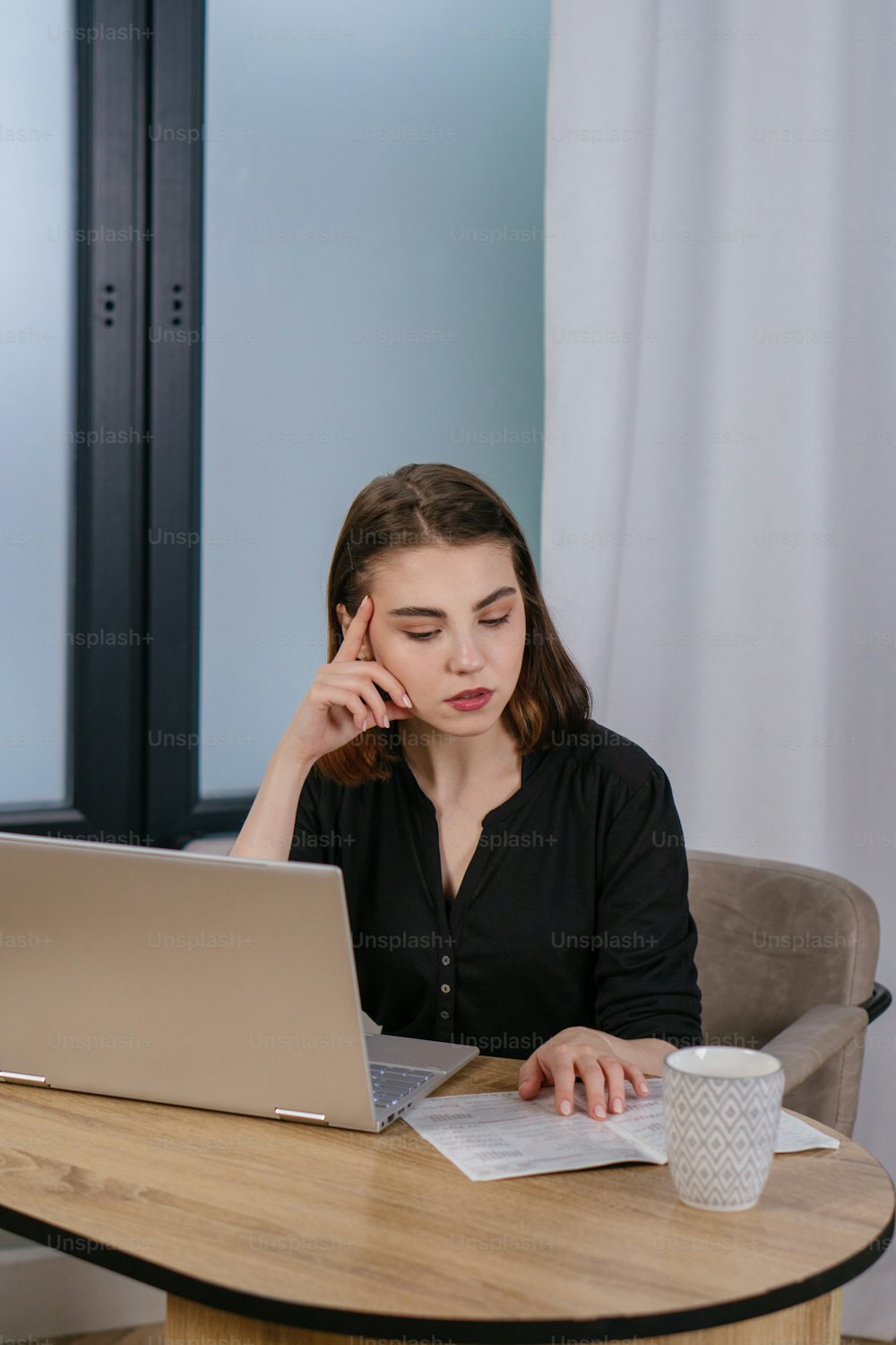 a woman sitting at a table using a laptop computer