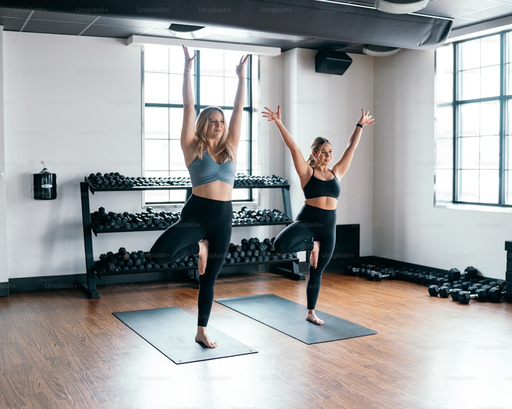 two women doing yoga poses in a gym