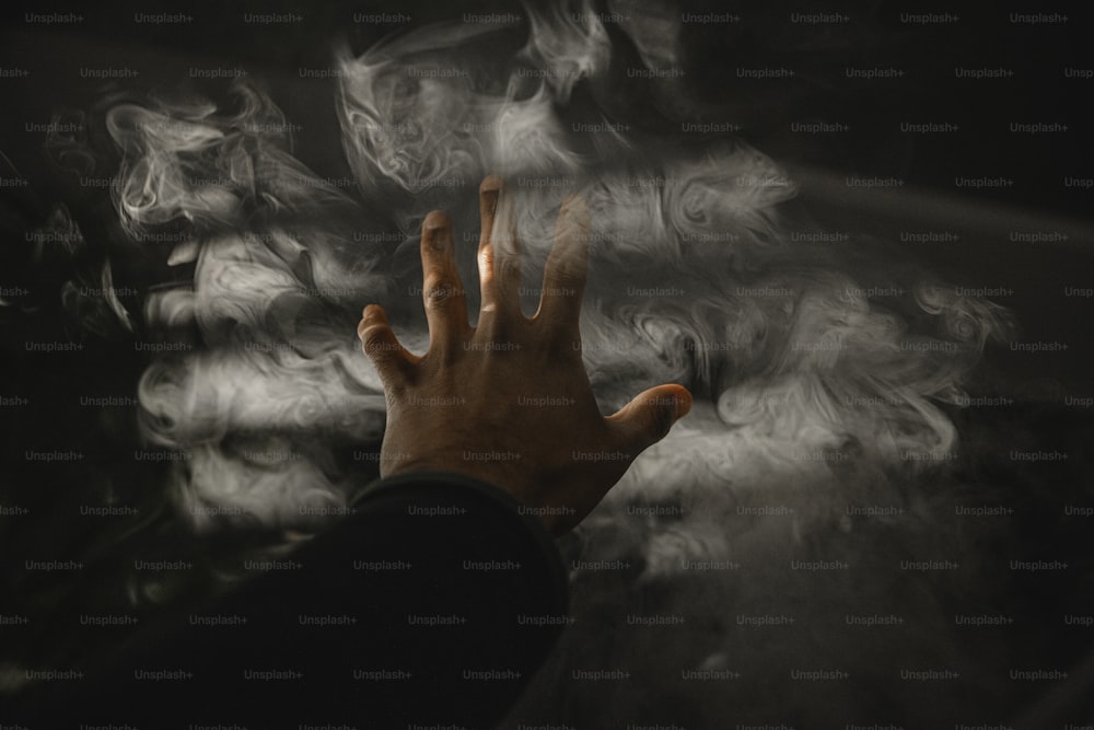 a person holding their hand out in front of smoke