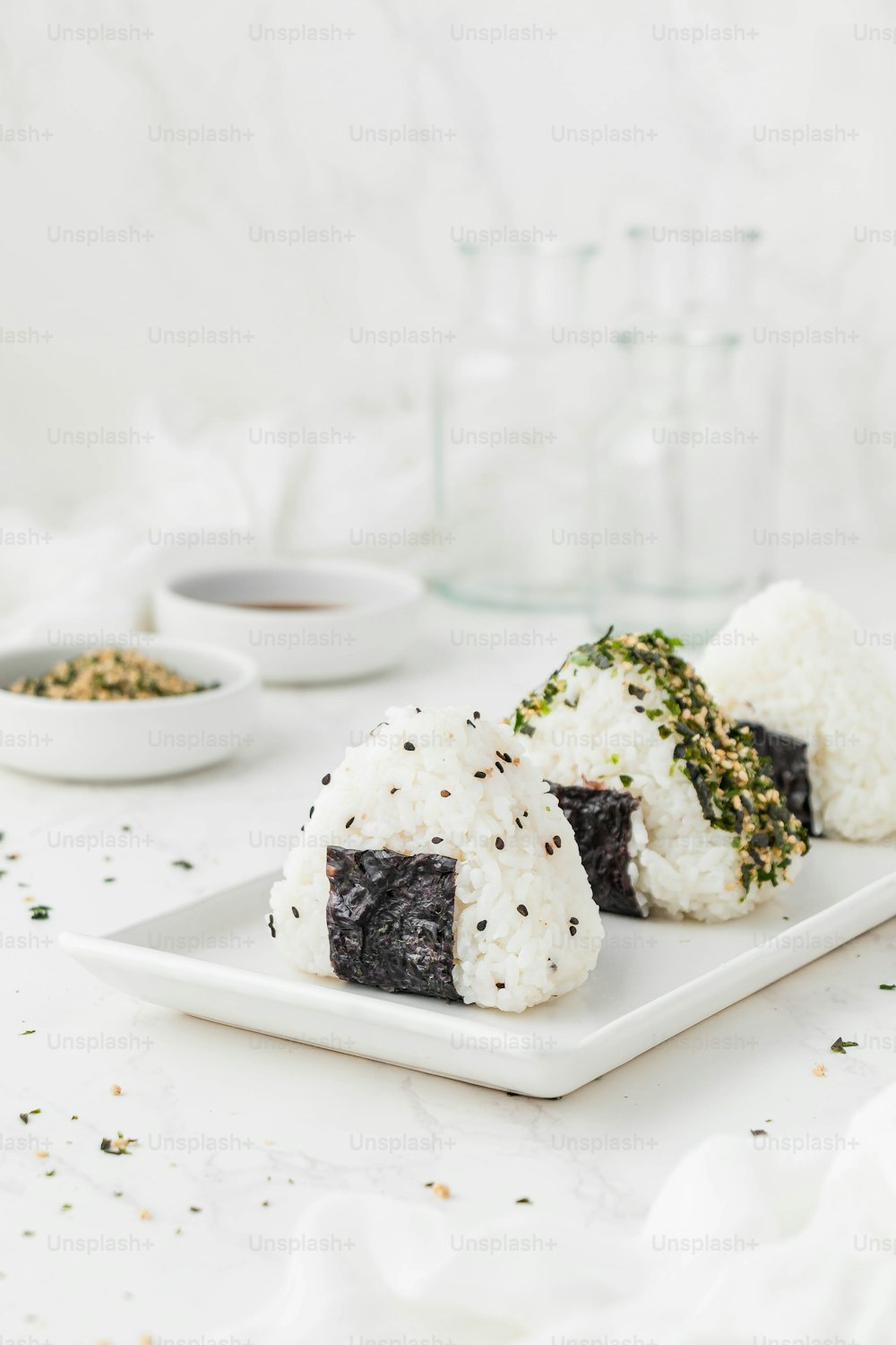 um prato branco coberto com sushi ao lado de tigelas de arroz