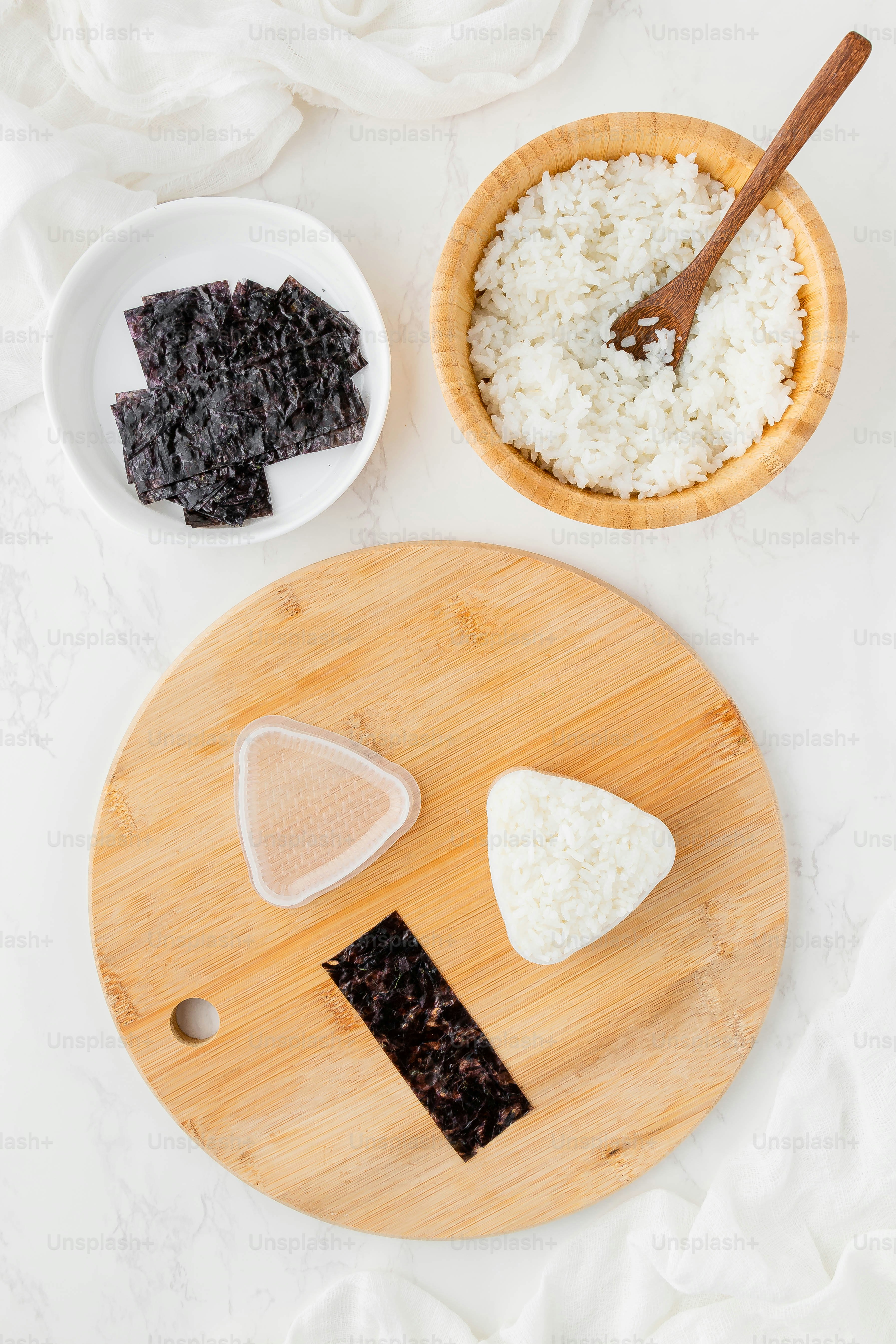a wooden cutting board topped with rice next to a bowl of rice