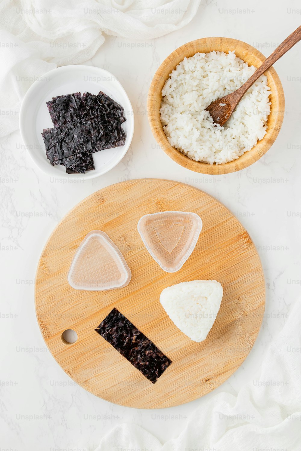 a wooden cutting board topped with slices of cheese next to a bowl of rice