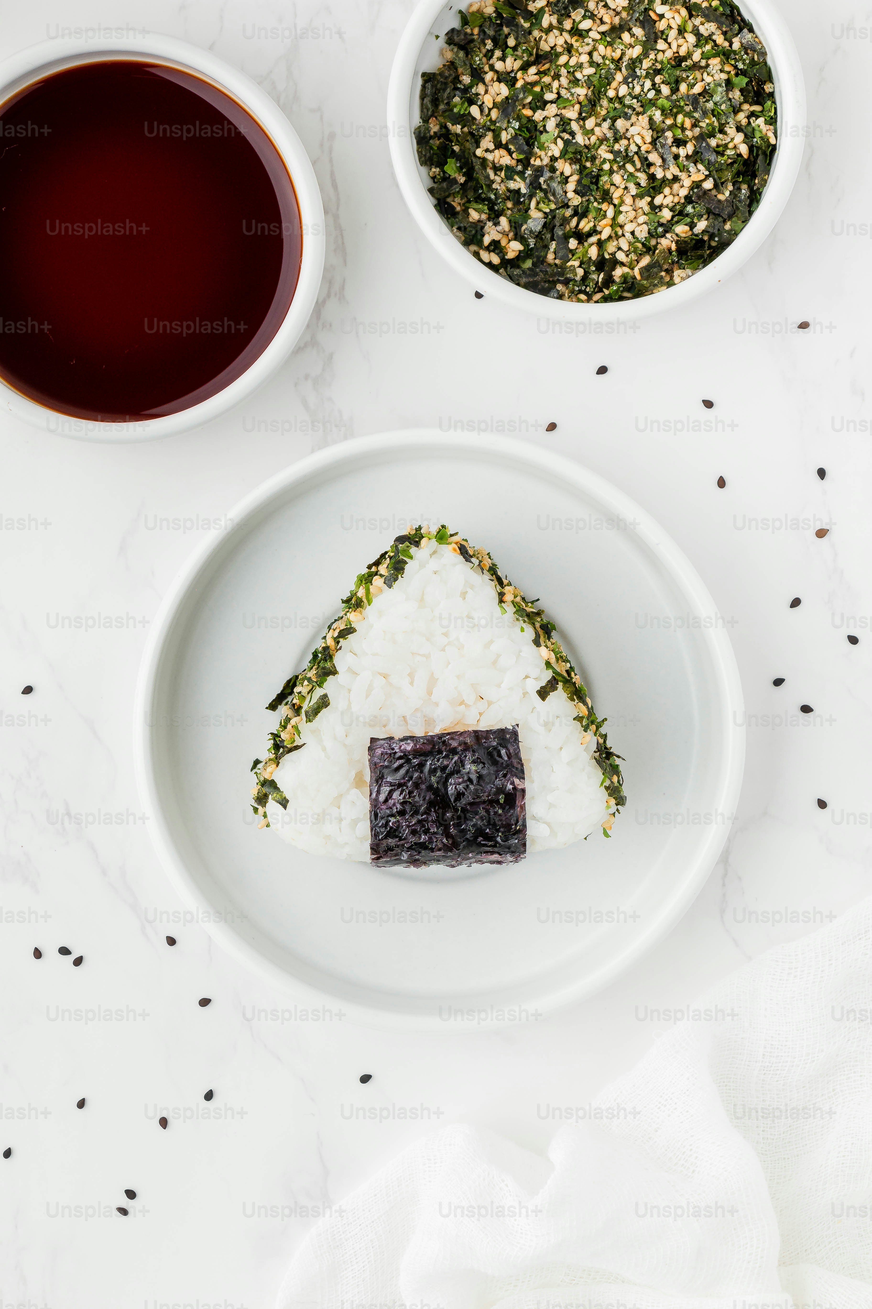 a white plate topped with sushi next to two bowls of sauce