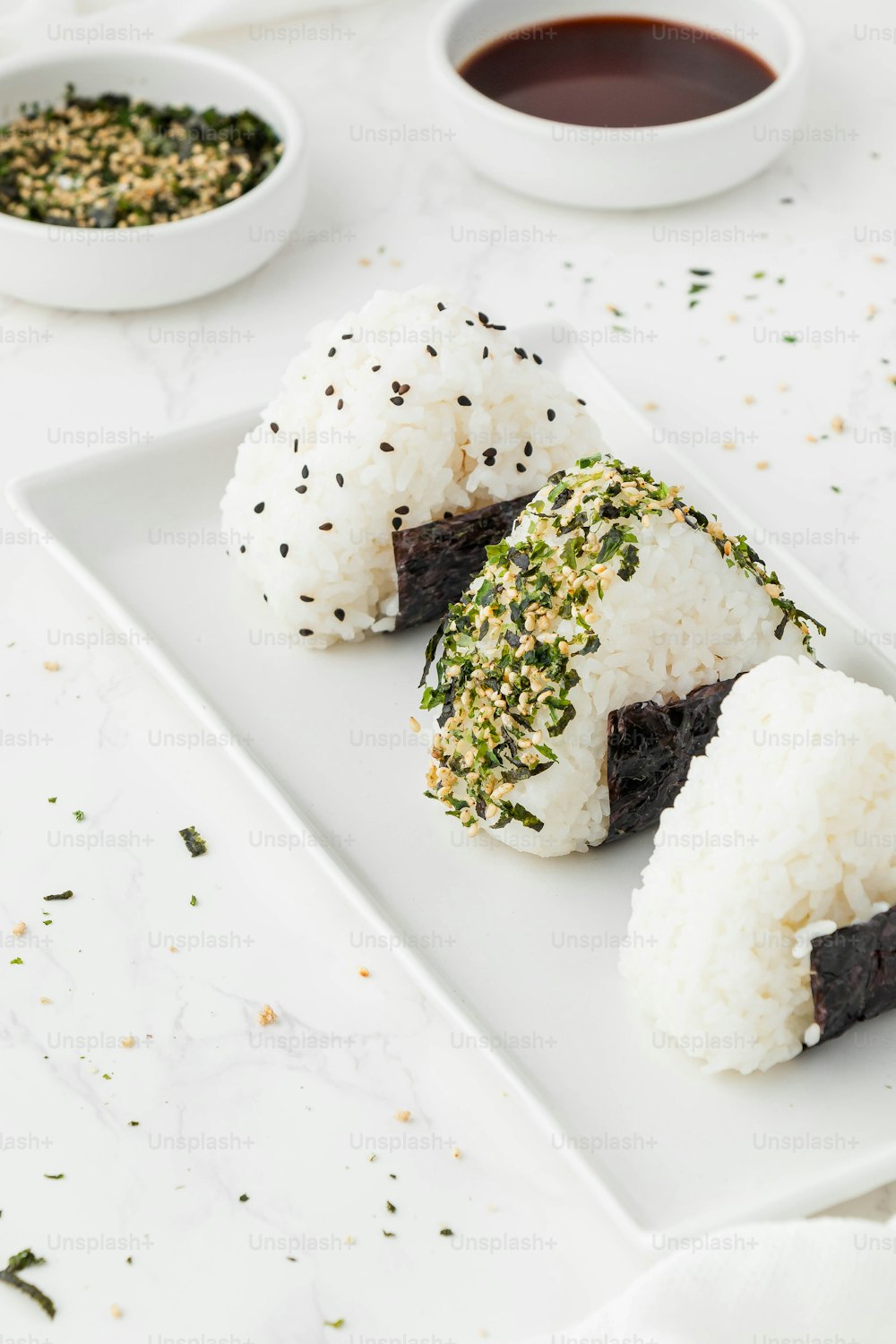 um prato branco coberto com sushi ao lado de uma tigela de molho