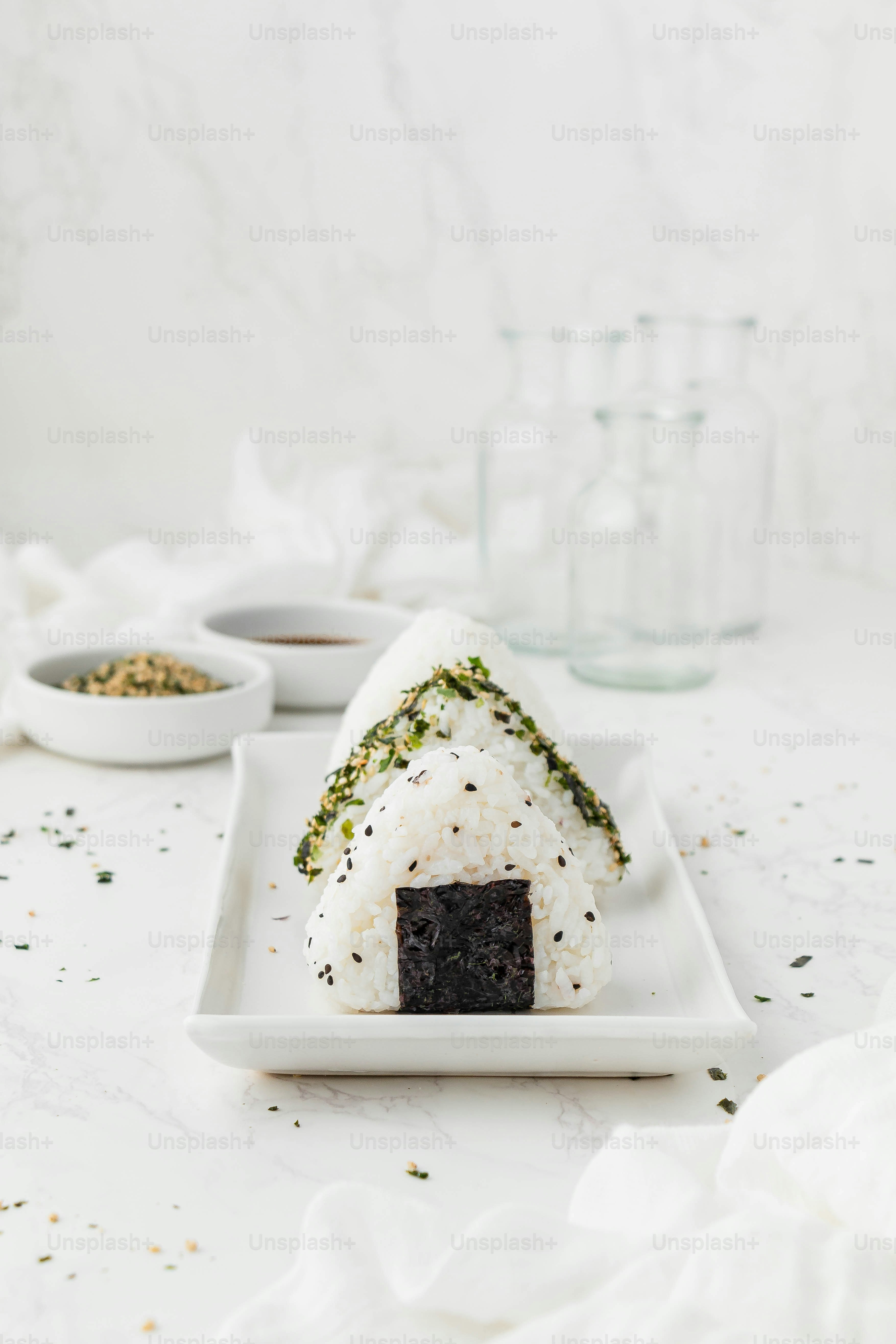 un plato blanco cubierto con sushi junto a tazones de salsa