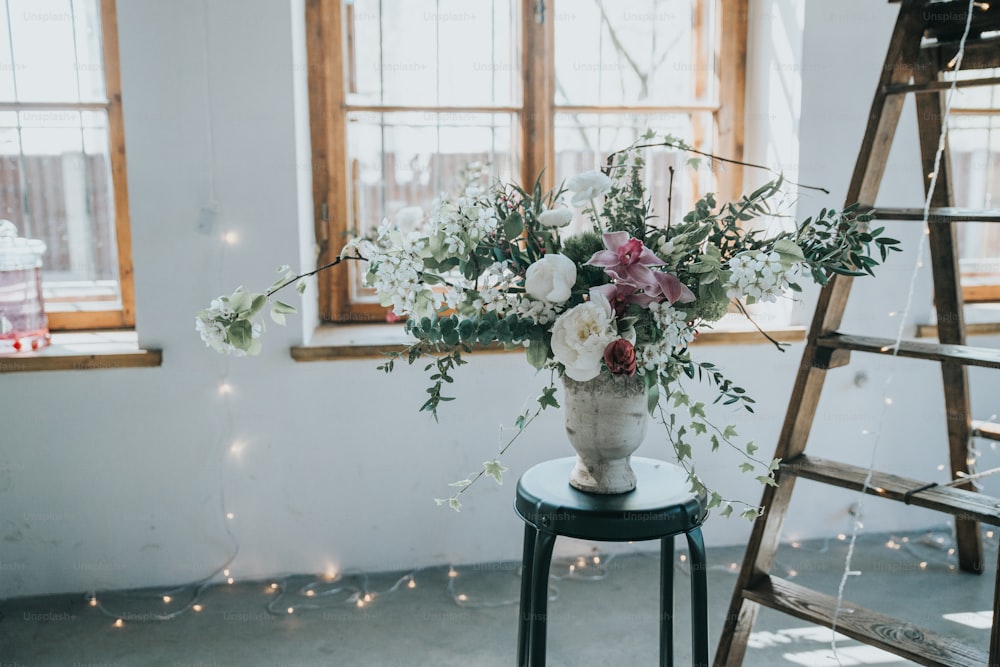 um vaso de flores sentado em uma mesa ao lado de uma escada