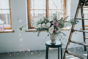 a vase of flowers sitting on a table next to a ladder