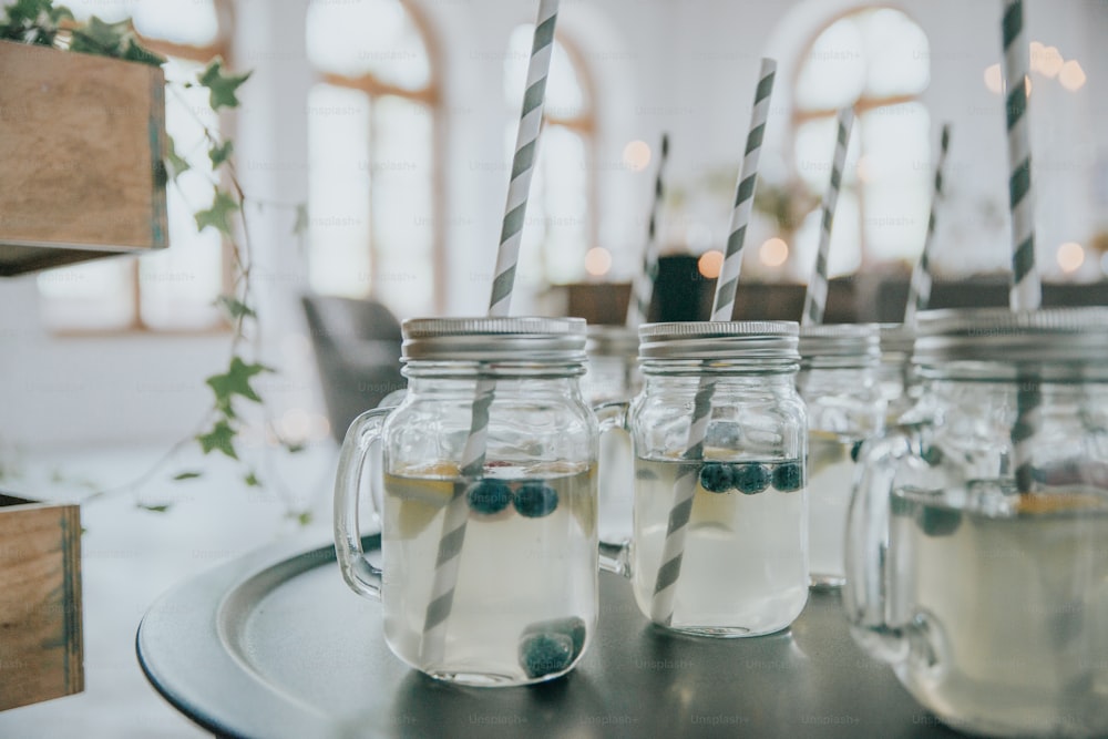 four mason jars filled with liquid and drinking straws