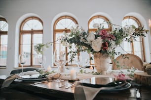 a vase of flowers on a table with place settings