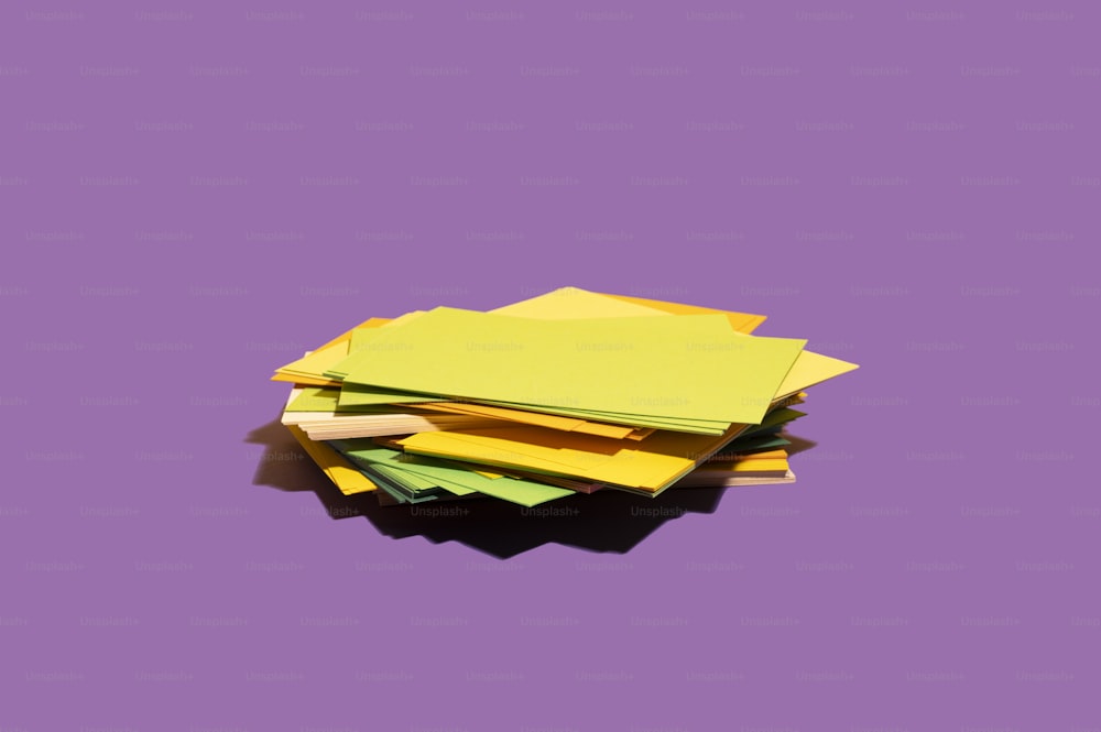 紫色の表面の上に座っている黄色い紙の山